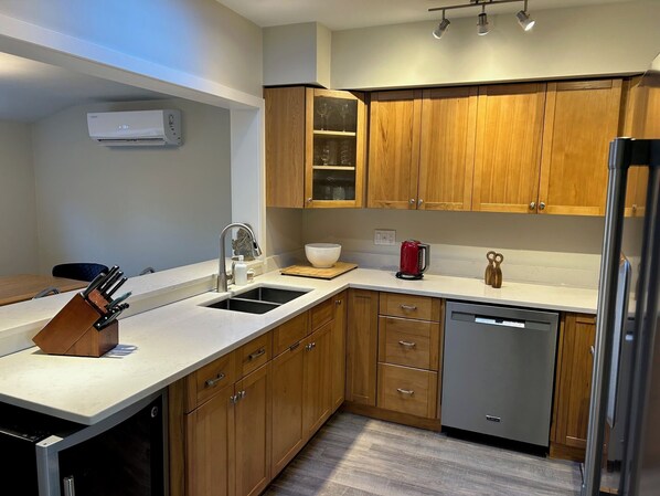 A modern kitchen with wooden cabinets, a stainless steel dishwasher, and a built-in oven.