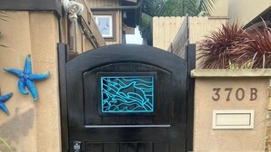 Une porte noire ornée d’un panneau décoratif bleu, un mur de pierre avec une boîte aux lettres et une étoile de mer bleue en guise de décoration.