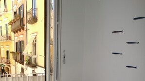 A room with a white table and wicker chairs, a sliding glass door leading to a balcony with a view of a yellow building. - Cozy home in a historic building in the heart of Amalfi, steps from the sea (AMALFI)