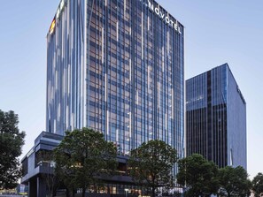 Moderni korkea hotellirakennus, jossa on suuri, selkeästi näkyvä «NOVOTEL»-kyltti, suuret ikkunat ja tyylikäs lasijulkisivu.