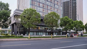 A modern hotel with a glass facade, a prominent 'NOVOTEL' sign, and a parking area in front. - Novotel Shanghai Qingpu Excellence (Shanghai)