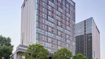Hotel stands tall with a sleek glass facade and vertical lines, set amidst a commercial district.