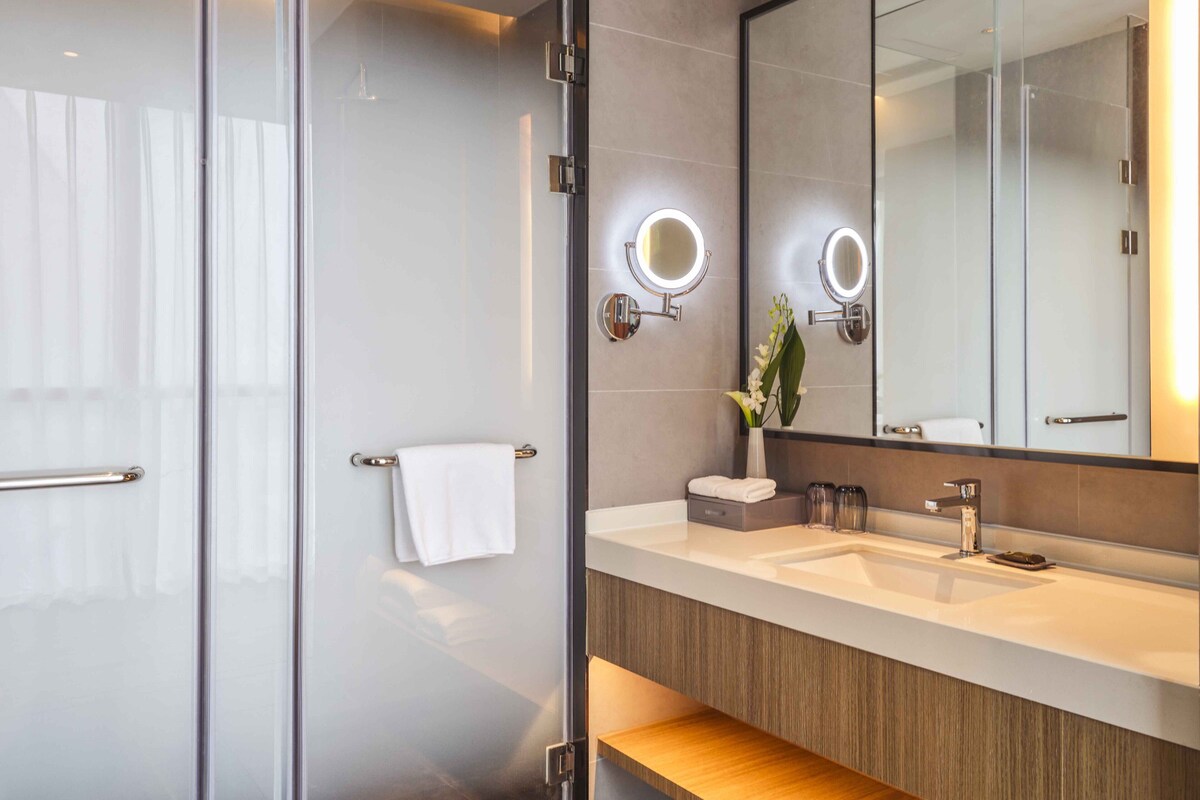 A modern bathroom with a glass shower enclosure, a vanity with a mirror, and a towel rack.