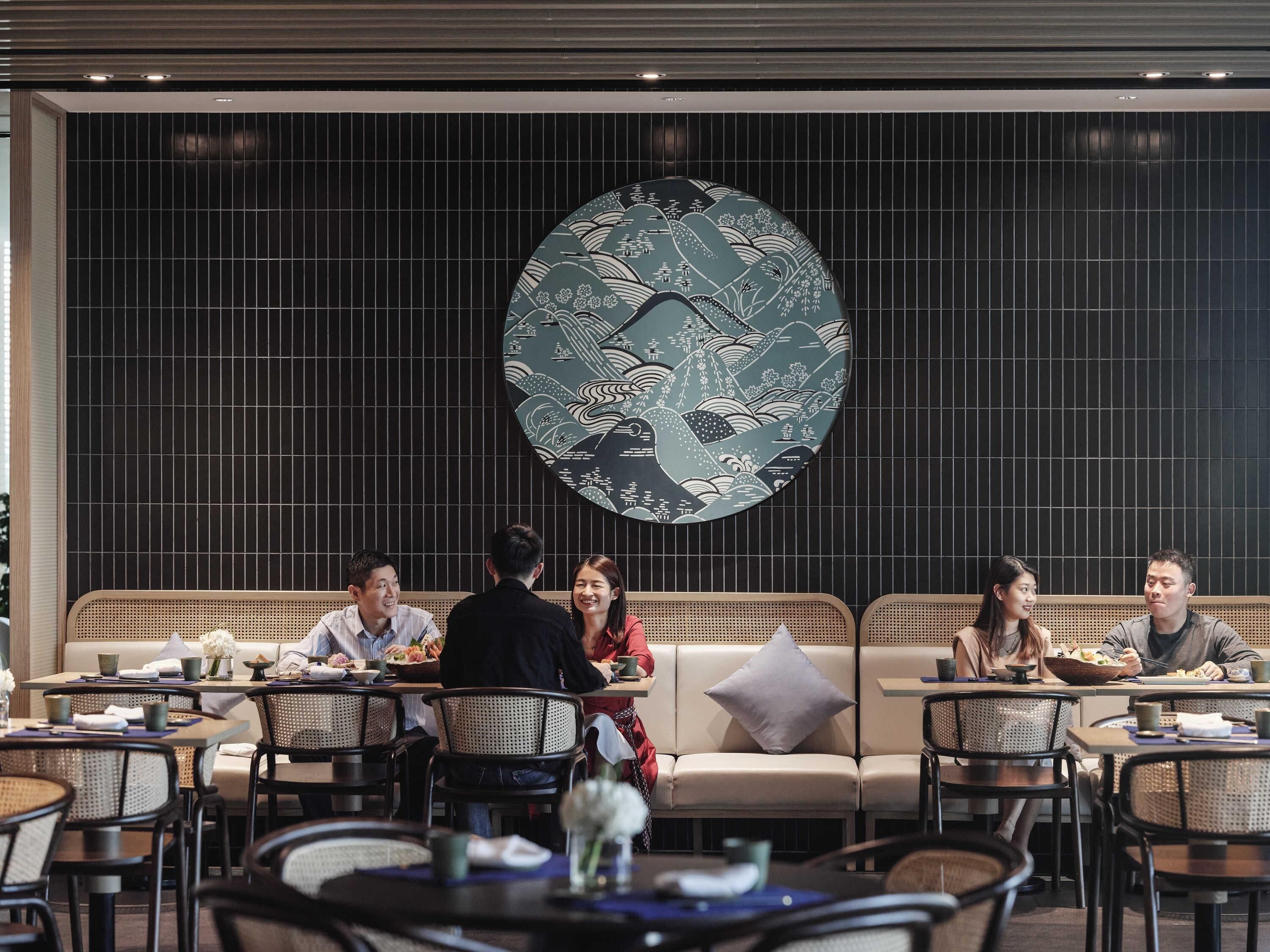 A restaurant with a large decorative clock, multiple seating areas, and a modern interior design.