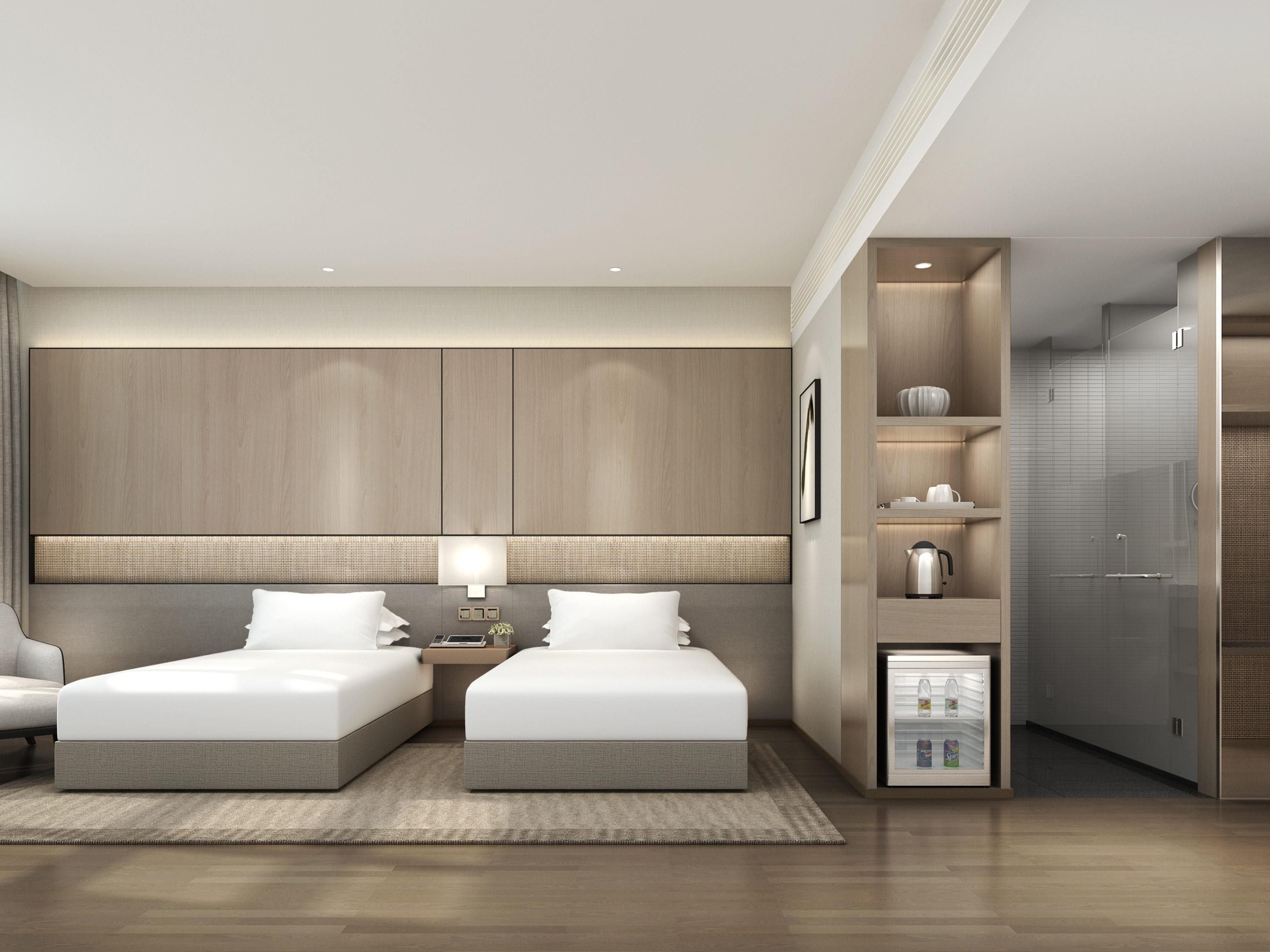 A modern hotel room with two beds, a bedside table, a nightstand, a built-in wardrobe, and a minibar.
