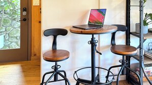 A room with a wooden door, a round mirror, a laptop on a small wooden table, and two black bar stools. - Modern-Rustic Canyon Studio with Kitchen Close to Hiking in Los Angeles. (Sierra Madre)