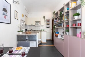 A compact kitchen with a microwave, toaster, and a small dining area with chairs and a table set for two.