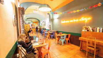 A restaurant interior with tables and chairs, a neon sign, and a piano.