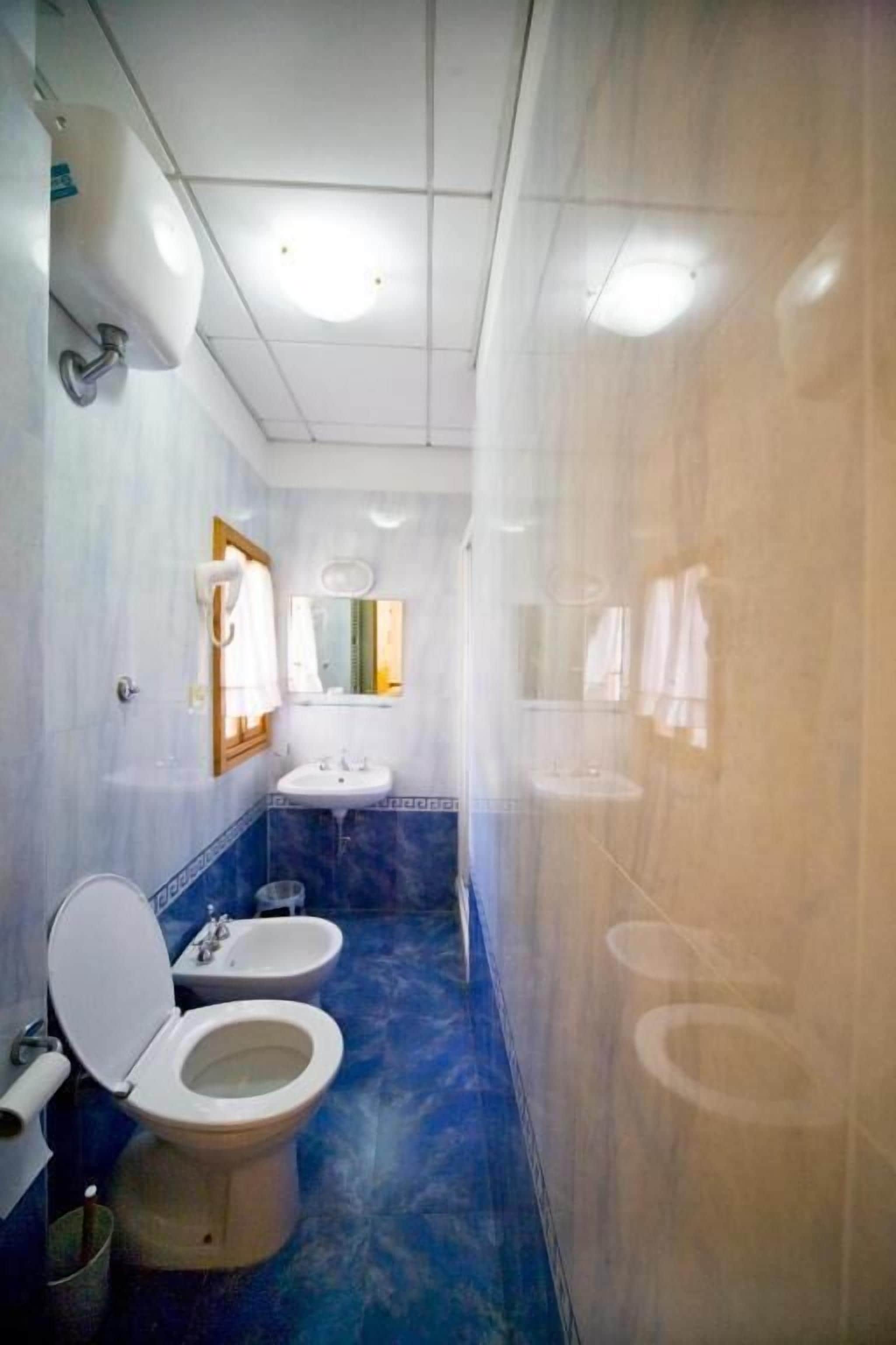 Un baño con inodoro, bidé y lavamanos.
