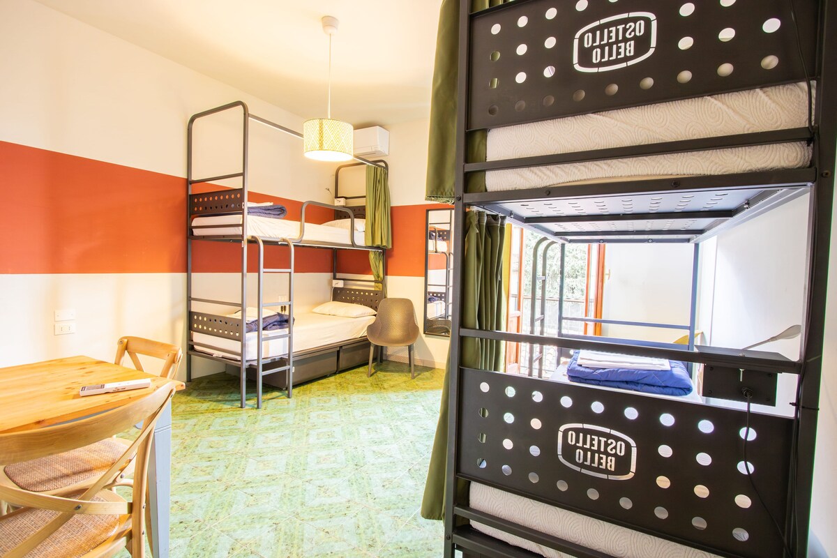 A bunk bed room with a desk and chair, a hanging light fixture, and a window with curtains.