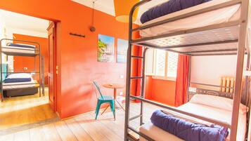 Habitación con literas, paredes anaranjadas, una mesita pequeña y una silla.