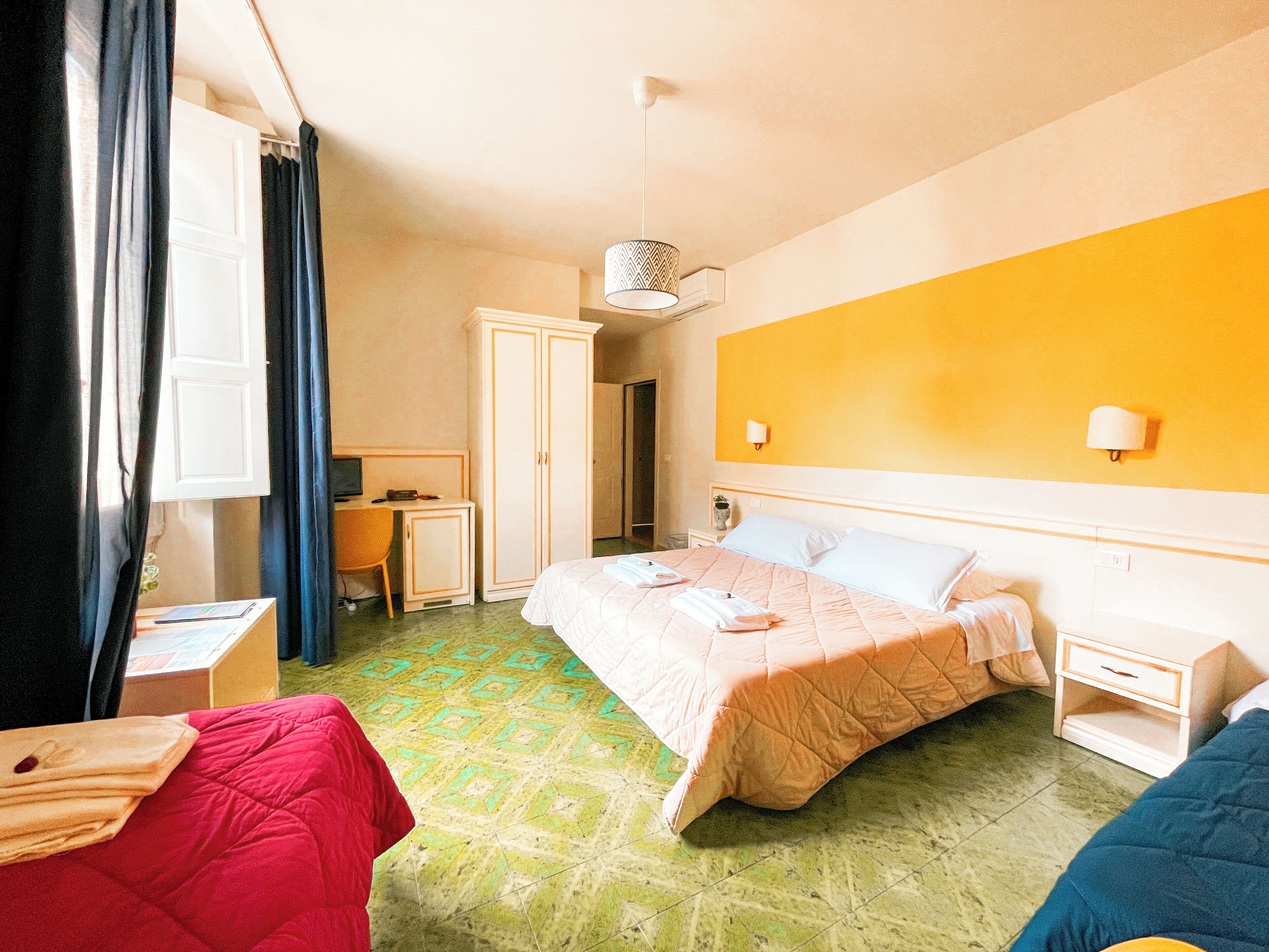 A hotel room with a bed, a desk, a wardrobe, and a bathroom.