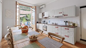A modern kitchen with white cabinets, a wooden countertop, and a dining area with a wooden table and chairs. - Ostello Bello Firenze (Florence)