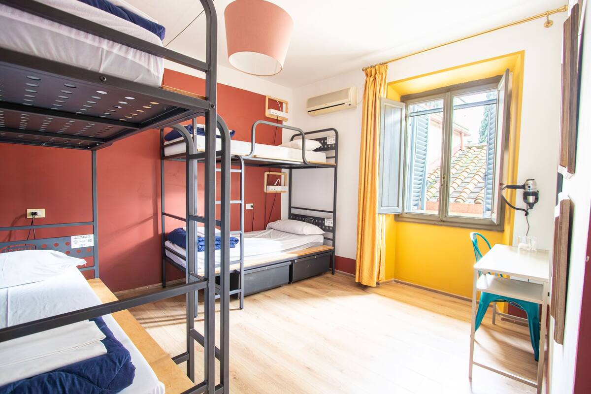Un dormitorio con literas, un escritorio y una ventana con cortinas.