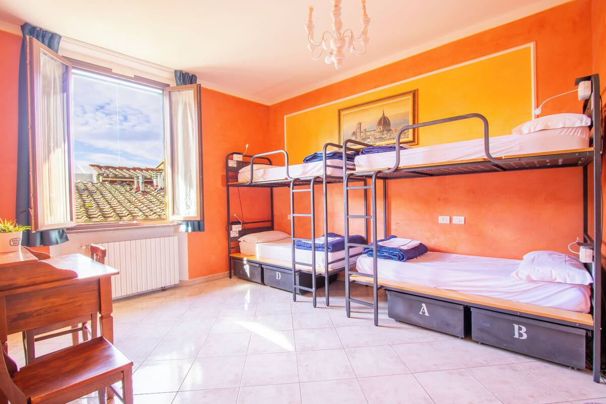Un dormitorio con literas, un escritorio y una ventana con vistas a la ciudad.