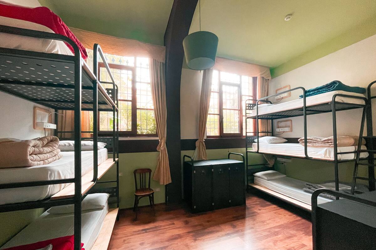 Un dormitorio con literas, un escritorio, una silla y una ventana con cortinas.