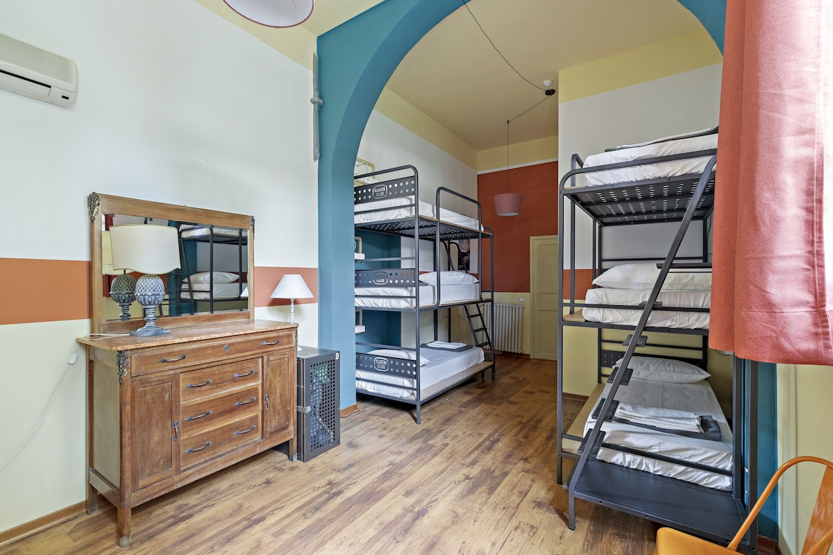 Une chambre de dortoir avec des lits superposés, une commode, un miroir et un radiateur.