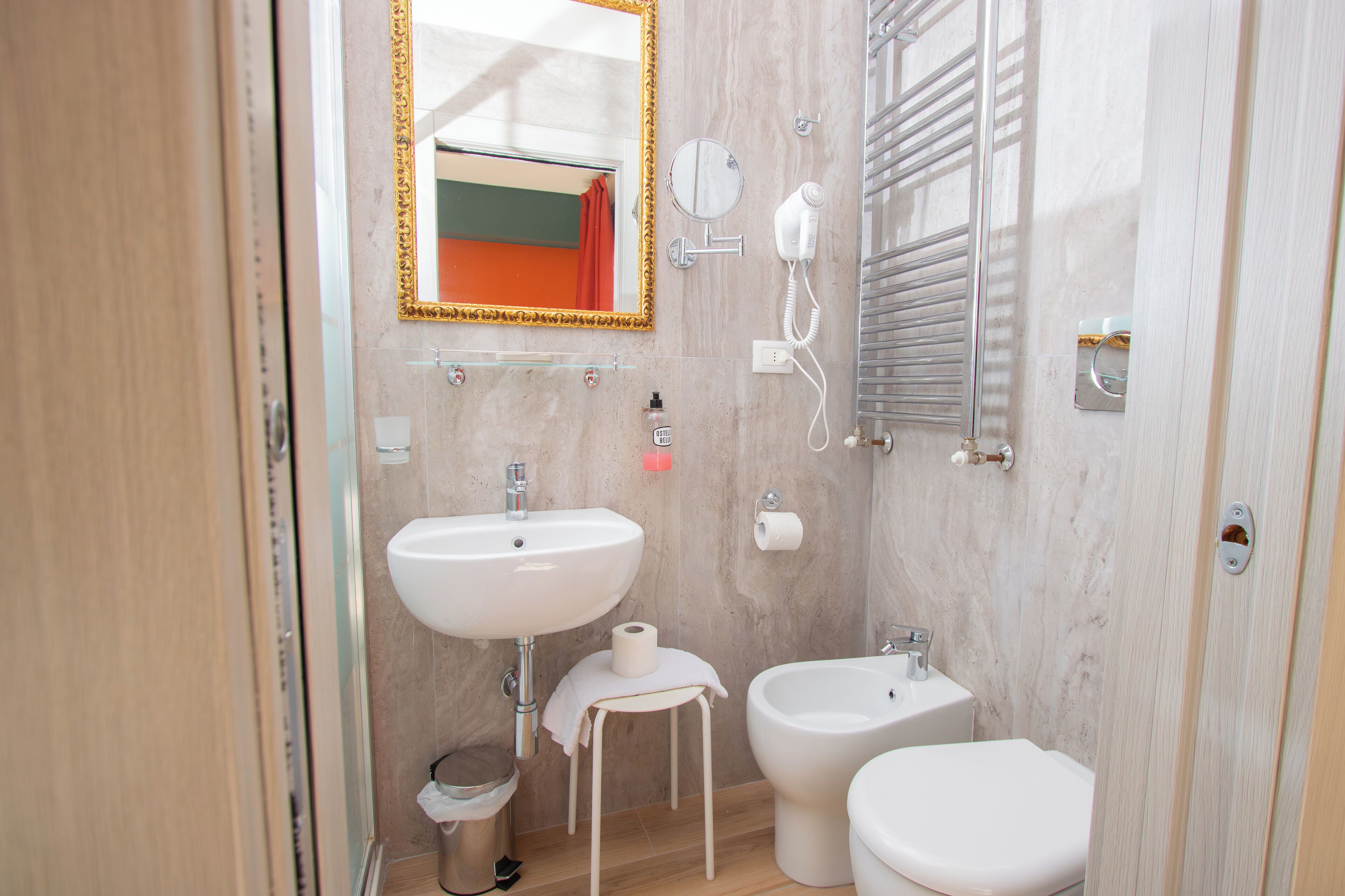 A bathroom with a sink, bidet, toilet, and a mirror with a gold frame.