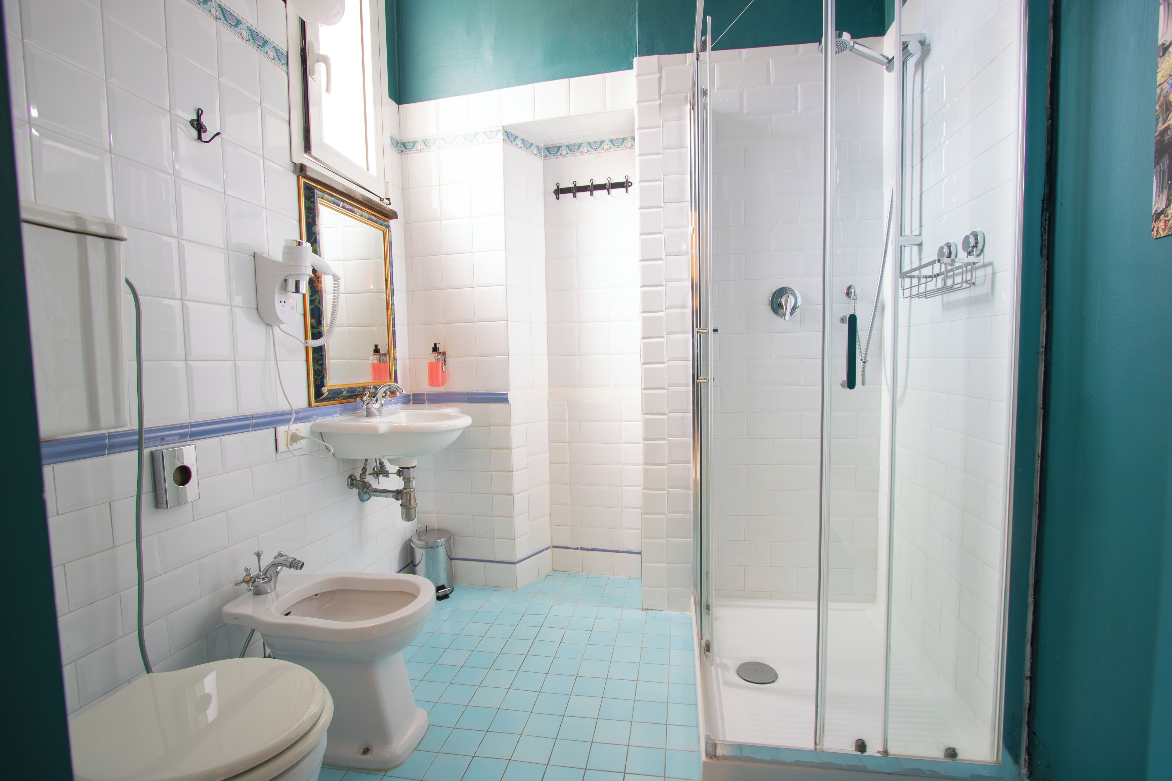 Une salle de bain comprenant des toilettes, un bidet, un lavabo et une douche à parois de verre.