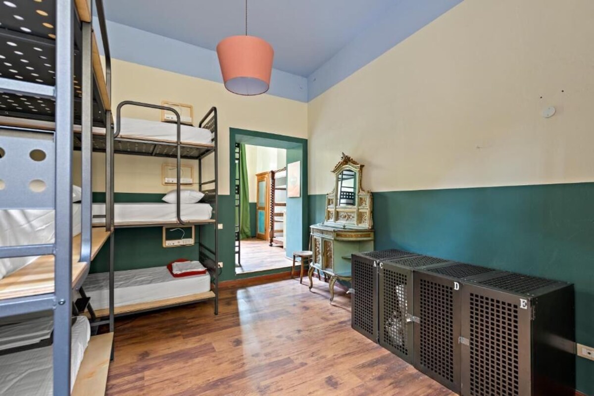 Une chambre de dortoir avec des lits superposés, un miroir et un radiateur.