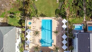 An aerial view of a resort with a central swimming pool surrounded by lounge chairs and palm trees. - Luxurious Ocean- Front 5th Floor – 3/3 Corner Unit – Sleeps 8 (Palm Coast)