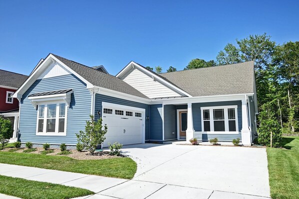 A two-story house with a garage, a covered porch, and a well-maintained lawn.