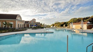 A large outdoor swimming pool with multiple lanes, surrounded by buildings and trees.