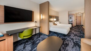 A hotel room with a desk, green chair, two beds, a large flat-screen TV, and a bathroom visible in the background. - Fairfield Inn & Suites by Marriott Columbus Canal Winchester (Canal Winchester)
