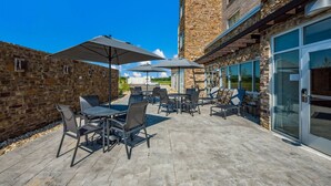 An outdoor patio with stone walls, tables, chairs, and umbrellas. - Fairfield Inn & Suites by Marriott Columbus Canal Winchester (Canal Winchester)