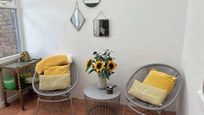 A cozy corner with two wicker chairs, a small round table, and a vase with sunflowers.