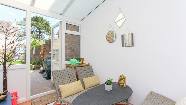 A sunlit patio with wicker furniture, a small round table, and decorative mirrors.