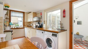 A compact kitchen with a washing machine, wooden countertops, and a window with a view.