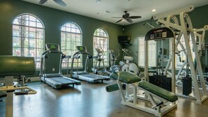 A gym with treadmills, weight machines, and a ceiling fan.