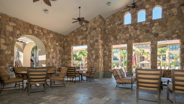 A spacious indoor area with stone walls, multiple seating arrangements, and large windows allowing natural light.