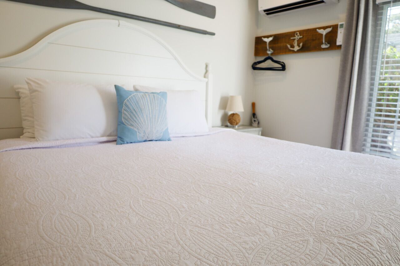 A neatly made bed with a white headboard, a blue pillow, and a white pillow.