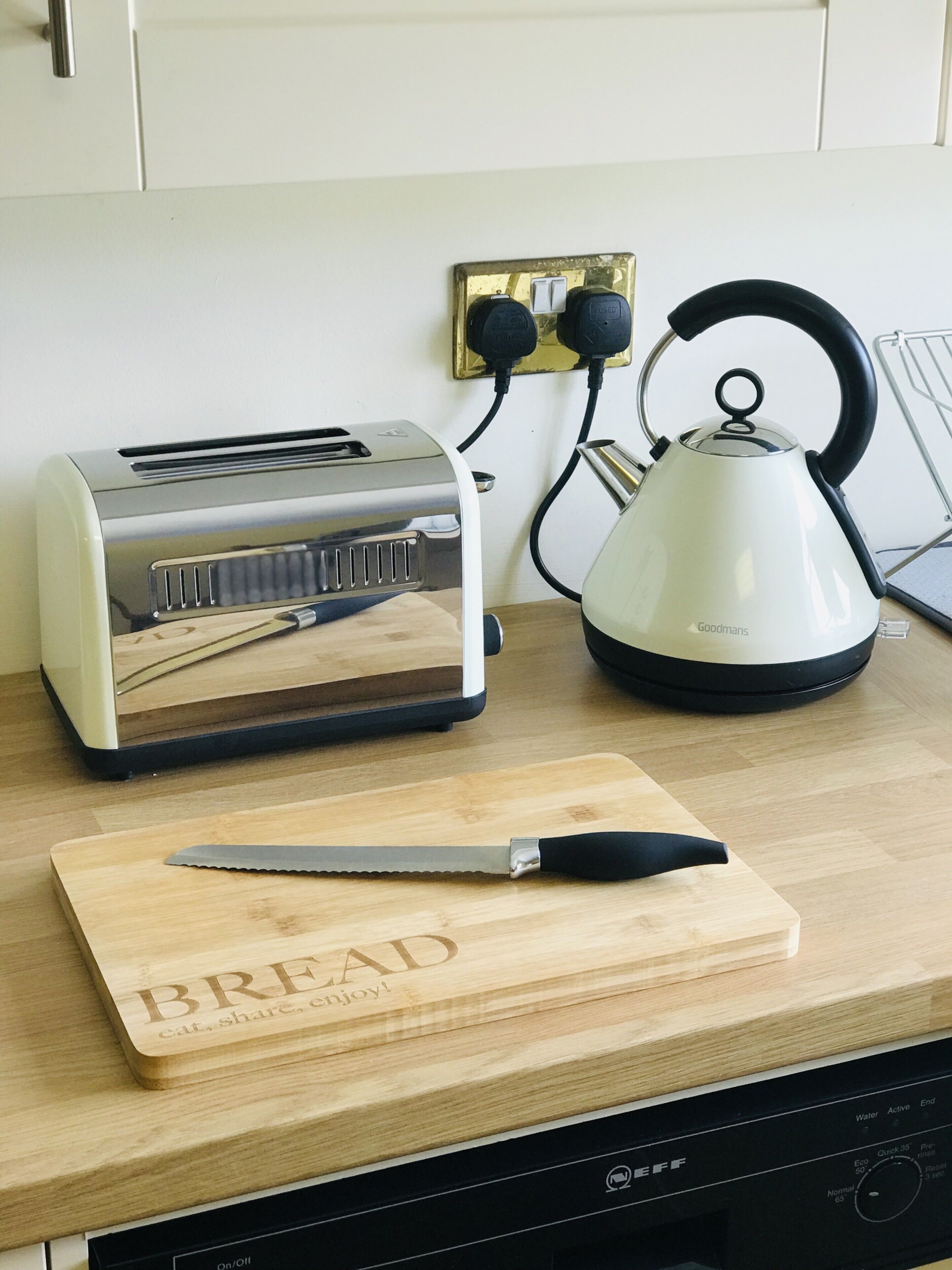 A kitchen counter with a toaster, kettle, and a cutting board with a knife.