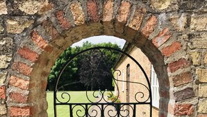 A wrought iron gate with intricate scrollwork, set within a brick archway.