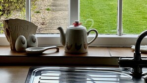A kitchen with a window view of a garden, a kettle, and some eggs.