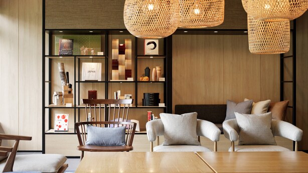 A modern interior with a wooden dining table, two sofas with cushions, a bookshelf, and woven pendant lights. - Fairfield by Marriott Gifu Takayama Shirakawa Go (Takayama)