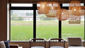 A dining area with a large window, wicker pendant lights, and a view of a green field. - Fairfield by Marriott Gifu Takayama Shirakawa Go (Takayama)
