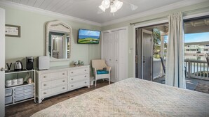 Une chambre à coucher comprenant un lit, une commode et un téléviseur diffusant un paysage.