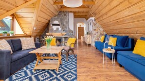 Un interior acogedor de madera con zona de comedor, sofás y una pared de piedra.