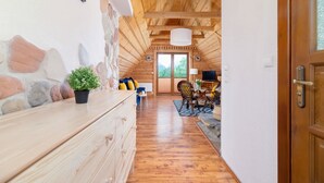 Un interior de madera con una pared de piedra, un tocador de madera, una planta en maceta, una silla, un televisor y una puerta.