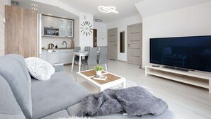 A modern living room with a grey sofa, a coffee table, and a TV on a stand. - Modern Apartment close to the Beach | Balcony | Parking (Darlowo)