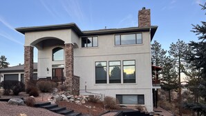 A modern two-story house with a stone facade, large windows, and a stone staircase leading to the entrance.