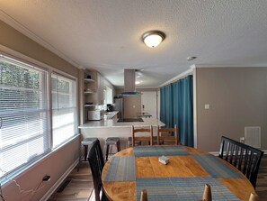 Un coin repas avec une table en bois, des chaises et une vue sur la cuisine.