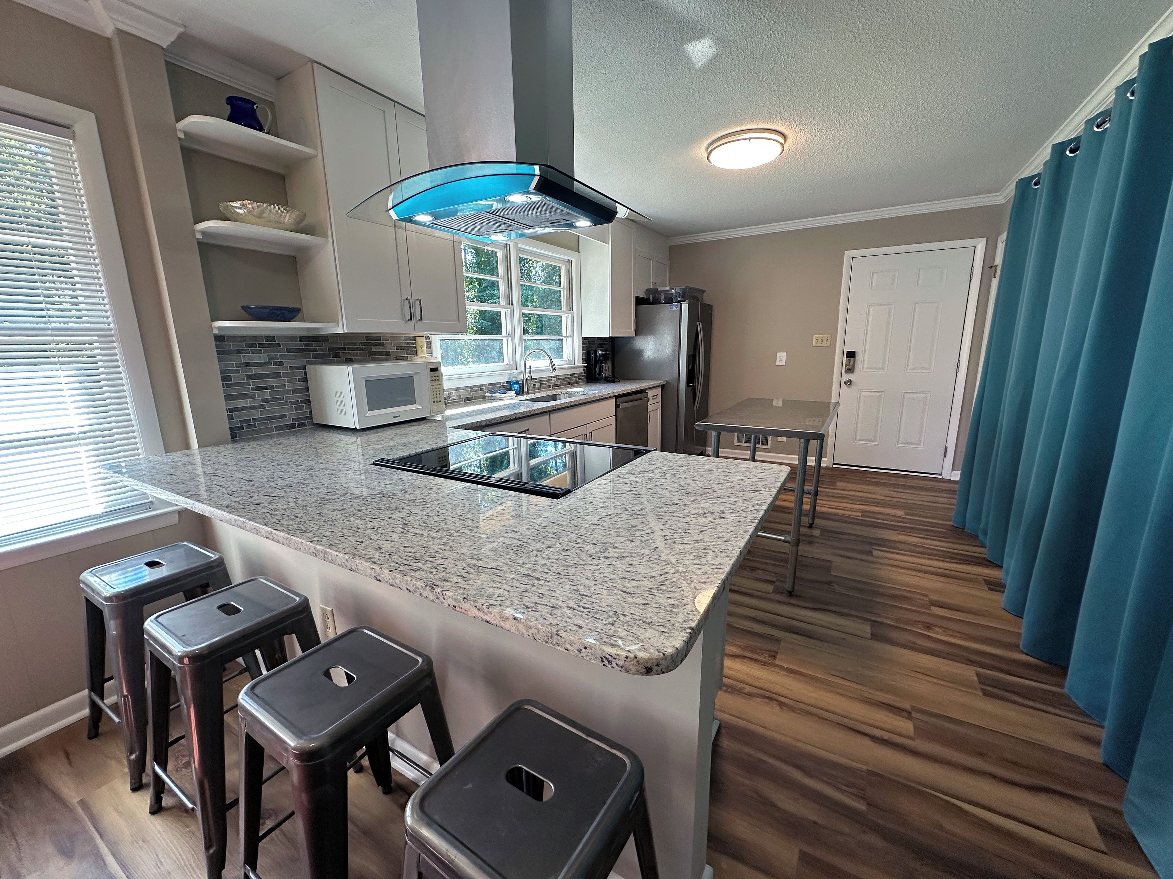 A modern kitchen with granite countertops, stainless steel appliances, and a central island with bar stools.