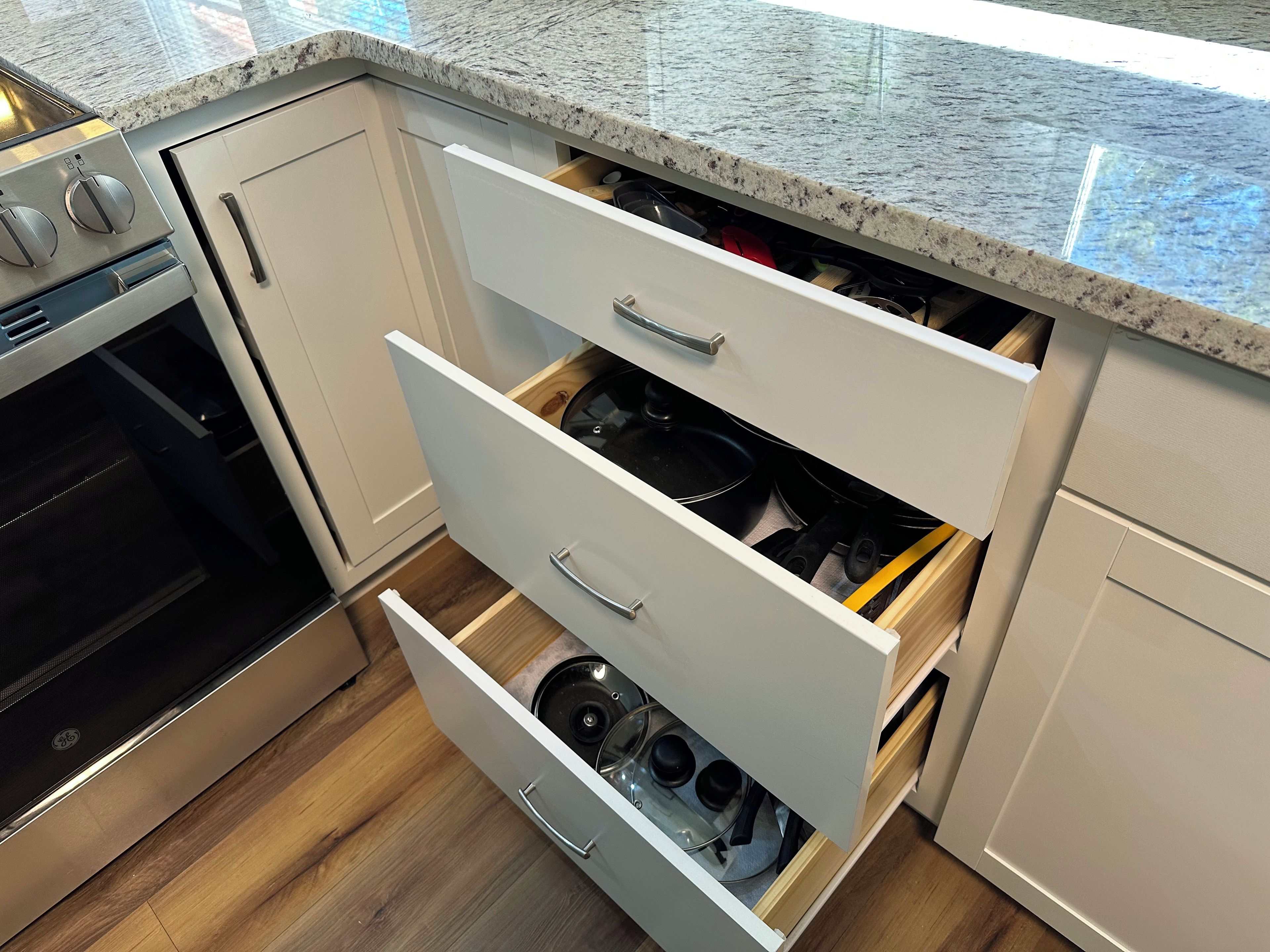 A kitchen with white cabinets, a stainless steel oven, and a granite countertop.