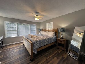 Une chambre à coucher avec un lit, des tables de chevet, un ventilateur de plafond et un grand miroir.