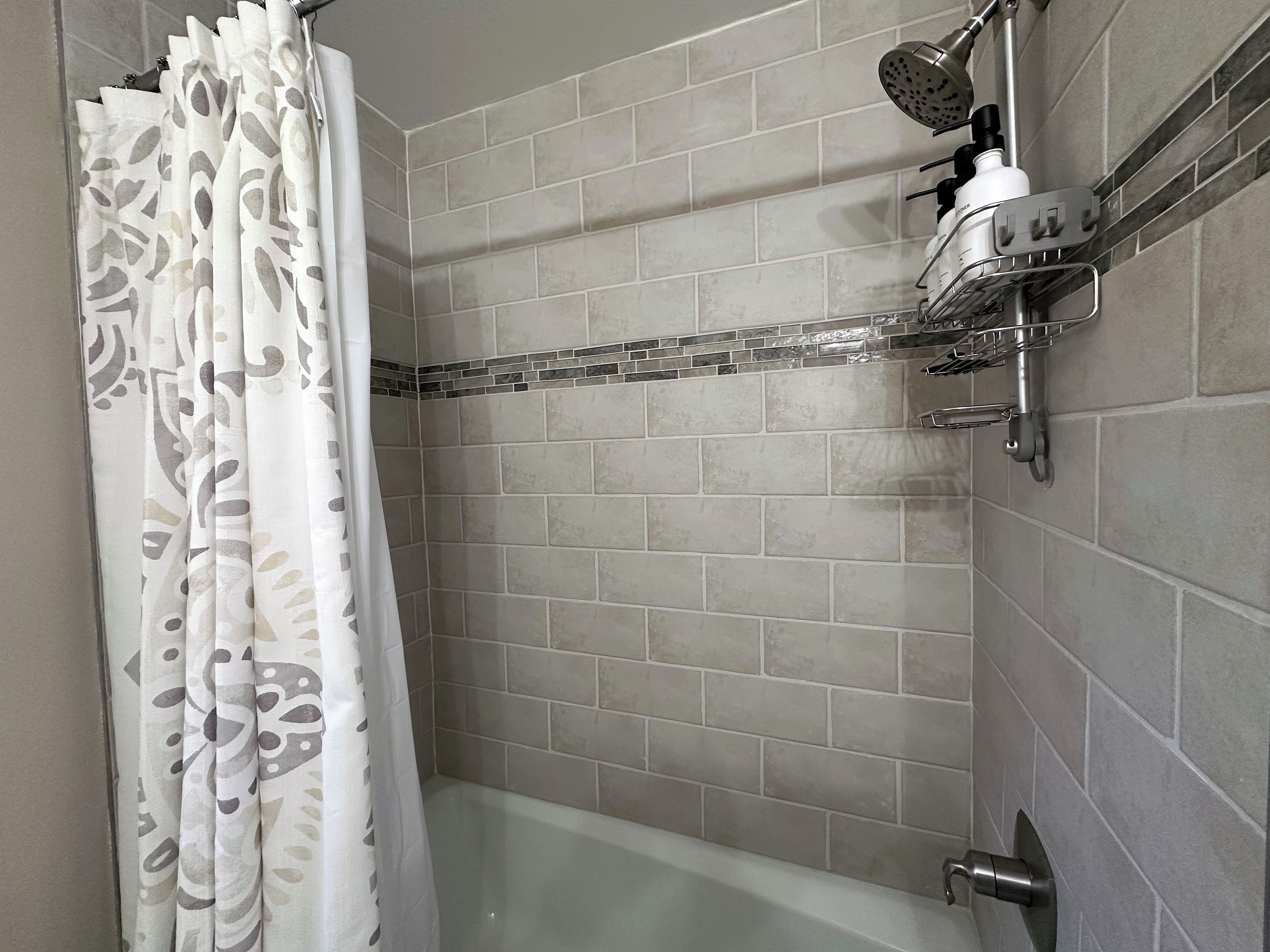 A bathroom with a shower, a bathtub, and a tiled wall.